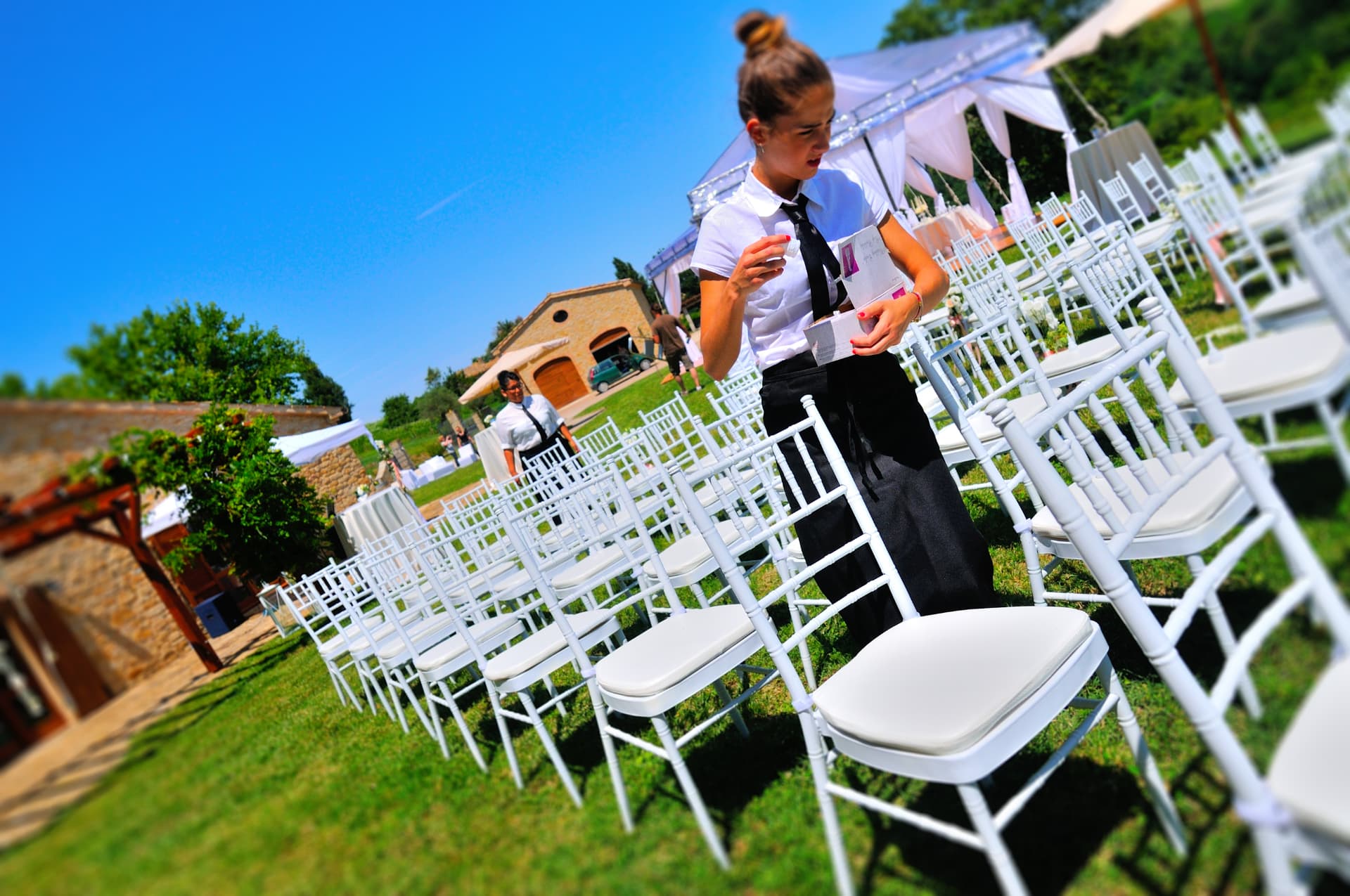Service team setting chiavari chairs for an outdoor wedding ceremony