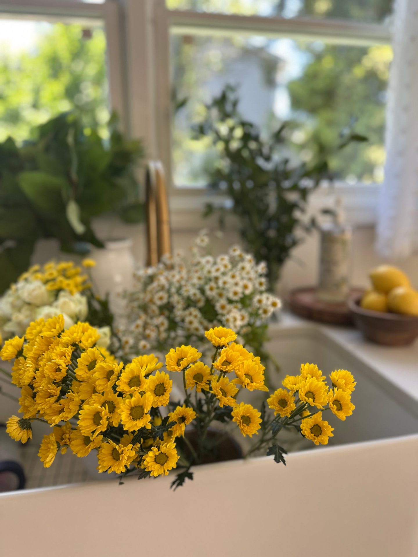 Yellow chrysanthemums and daisies arranged in a kitchen setting
