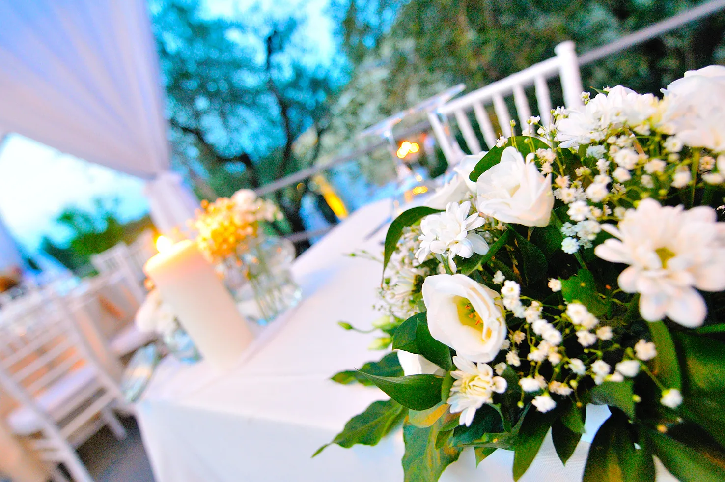 White rose centerpiece with candlelight at a wedding dinner