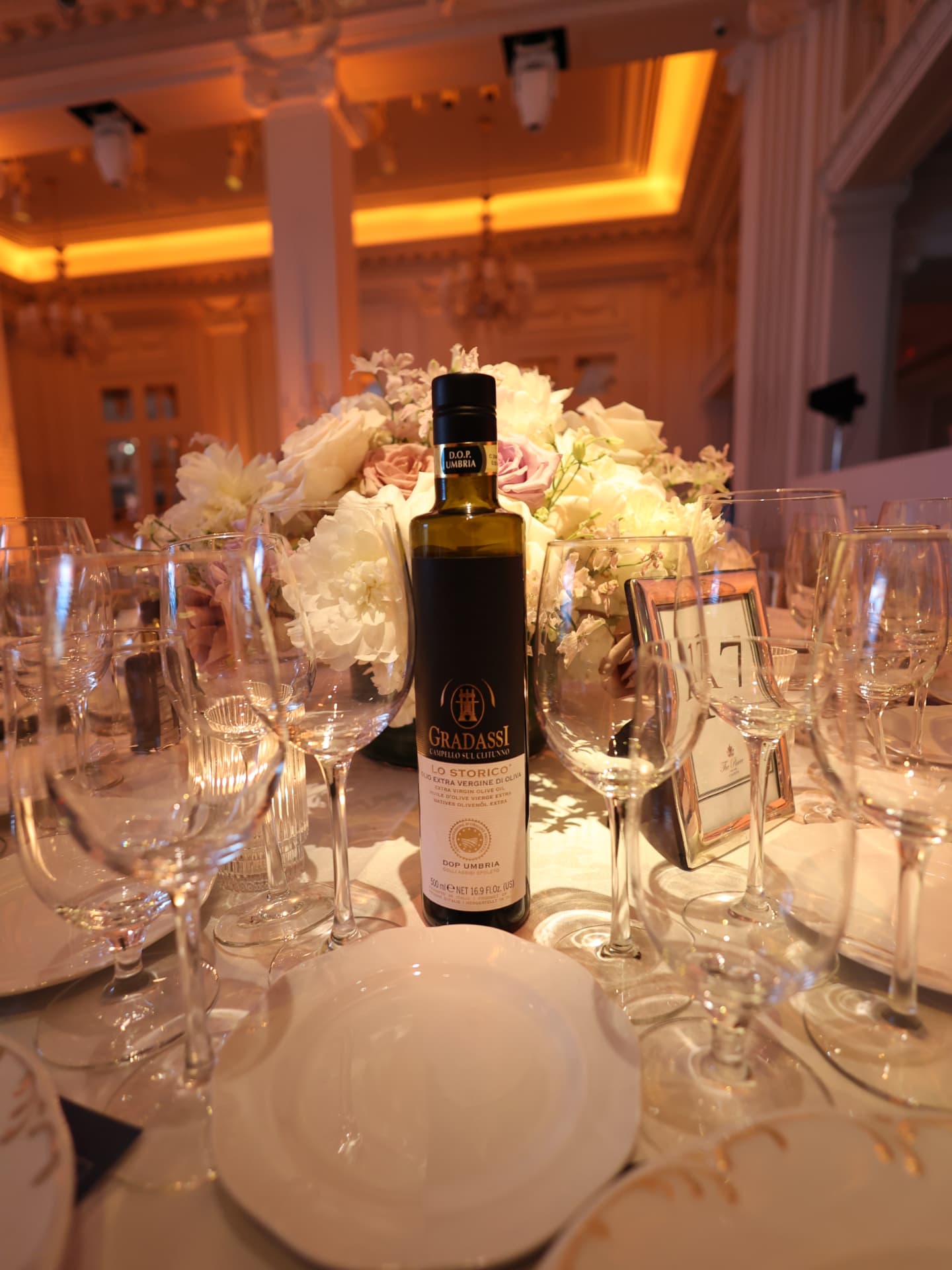 Wedding table centerpiece with white roses and Italian olive oil bottle