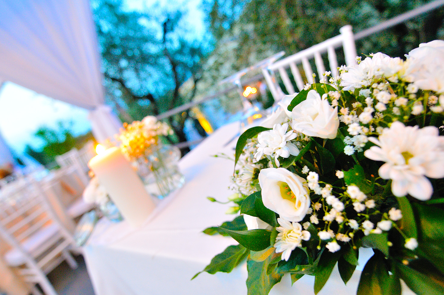 White rose centerpiece with candlelight at a wedding dinner