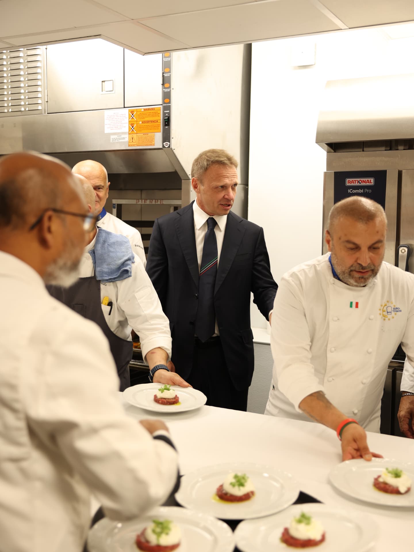 Chef Fabrizio Facchini with chefs and dignitaries in a professional kitchen
