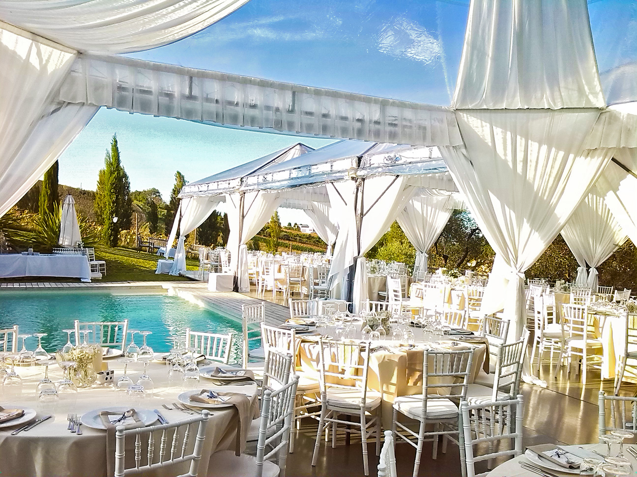 Poolside private event catering setup with draped tenting and set dining tables
