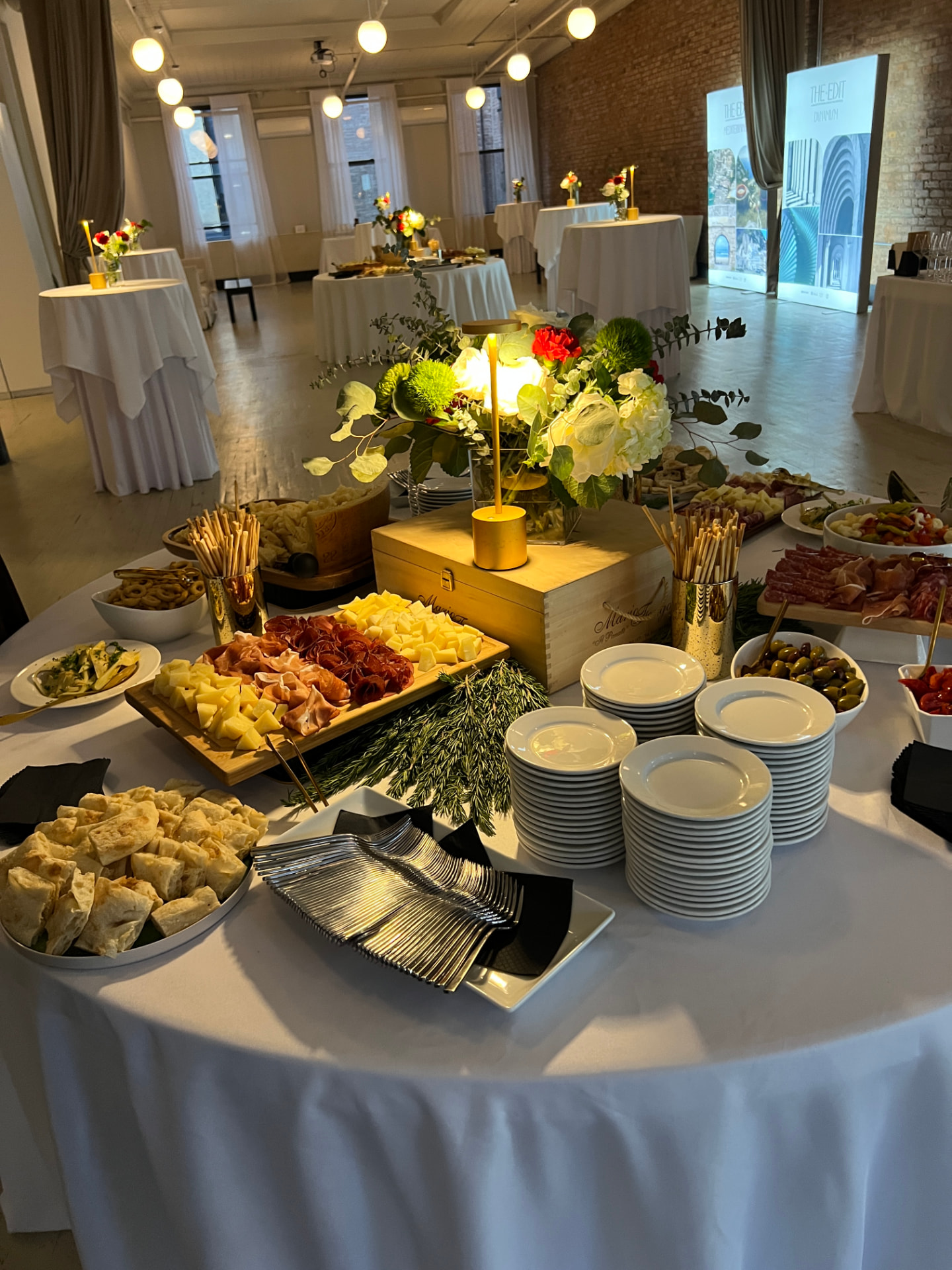 Elegant Italian catering display with antipasti, cheeses, cured meats, fresh bread and flowers