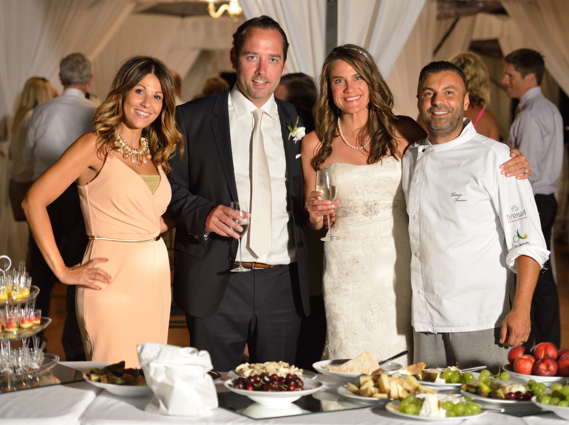 Chef Fabrizio Facchini with the newlyweds beside a wedding cheese and fruit display
